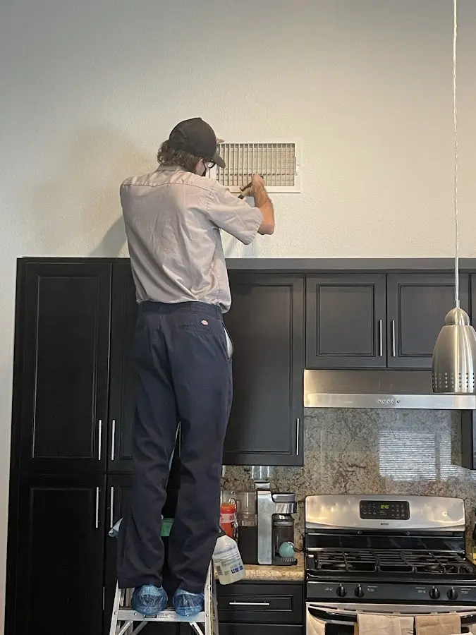 Technician inspecting an air vent during HVAC service in Nephi